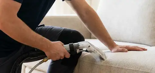 Professional upholstery cleaner deep-cleaning a fabric sofa with a handheld extraction tool, Colorado Springs, CO.